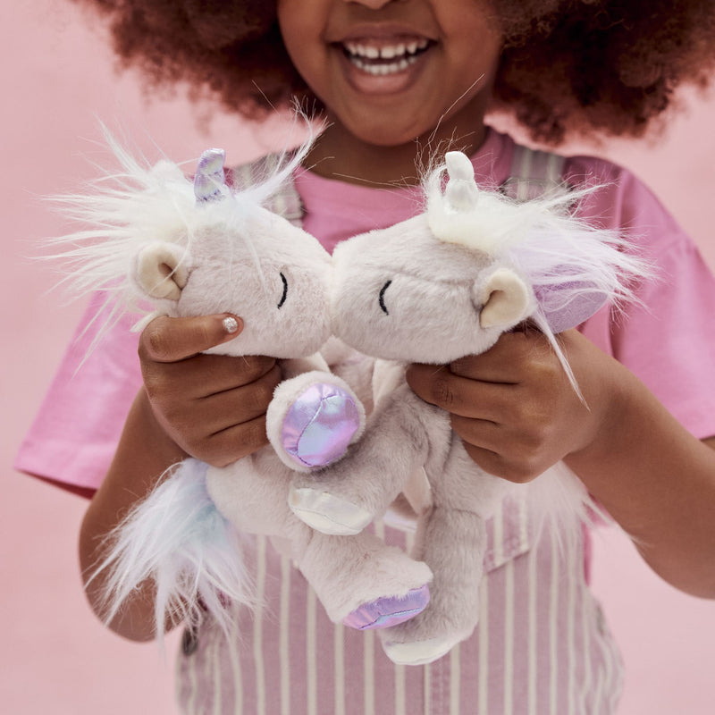 Binky Baby Unicorn - Sparkle by Dinkum Pets shown as a soft white plush unicorn with a pink horn held alongside another unicorn by a smiling child