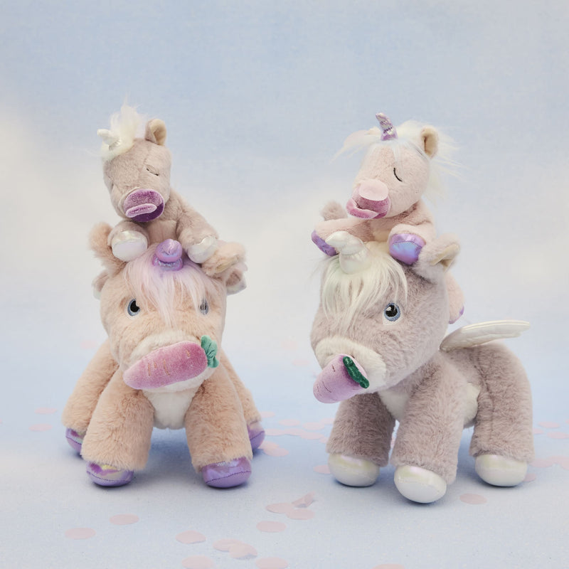Binky Baby Unicorn - Sparkle by Dinkum Pets perched on a larger pastel unicorn plush toy in a soft imaginative play scene